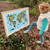 Young child pointing to a framed Whole Wide World Kids' Map by AmazingWorld with a stick in woodland