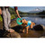 Person on some rocks playing with a dog in the water while the dog is wearing Person paddleboarding with a dog on the board facing the camera while wearing the Ruffwear Float Coat Dog Life Jacket in blue