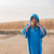 Person standing wearing the dryrobe Organic Towelling Cobalt Blue Robe on a beach close up with the hood up