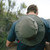 Person facing away from camera in the outdoors with the Tilley T3 Olive Wanderer Hat carried on their back so you get a top view of the hat and brim