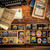 Wood table scattered with vintage travel books and typewriter with a post card and two trays full of patches from The Adventure Patch Company