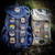 Two rucksacks, one blue and one light grey sitting against a mossy tree trunk displaying many sewn patches from The Adventure Patch Company