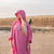 Person wearing the Dryrobe Organic Towelling Pink Robe on the beach with the hood up