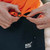 Close up of person wearing Mac in a Sac Men's Venture Ultralite Neon Orange Running Jacket with close up of toggle on the hem
