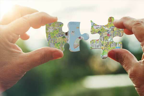 Hands holding jigsaw pieces with a map image