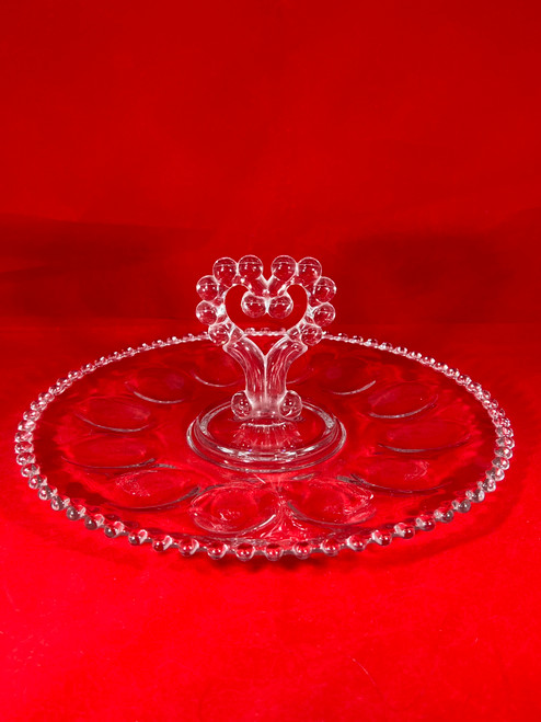 The beautiful Imperial Glass Candlewick and Heart Deviled Egg Server sitting on a piece of red felt higlighting its elegance and pristine condition.