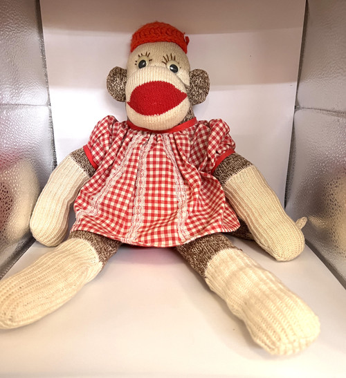 Sock monkey with red gingham dress and big eyelashes.