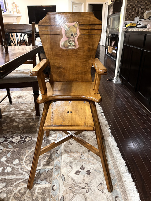 Wooden 1950s high chair sitting in a kitchen.