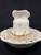 Neck and front view of the 1900s wash pitcher of cream and gold sitting in the was basin of the same design.