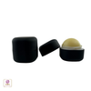 A matte black lip balm ball with its lid open next to the same lip balm ball container with its lid locked closed