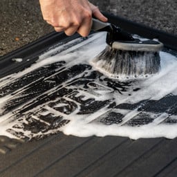 DriveDen boot mat being cleaned with a soft brush and soapy water