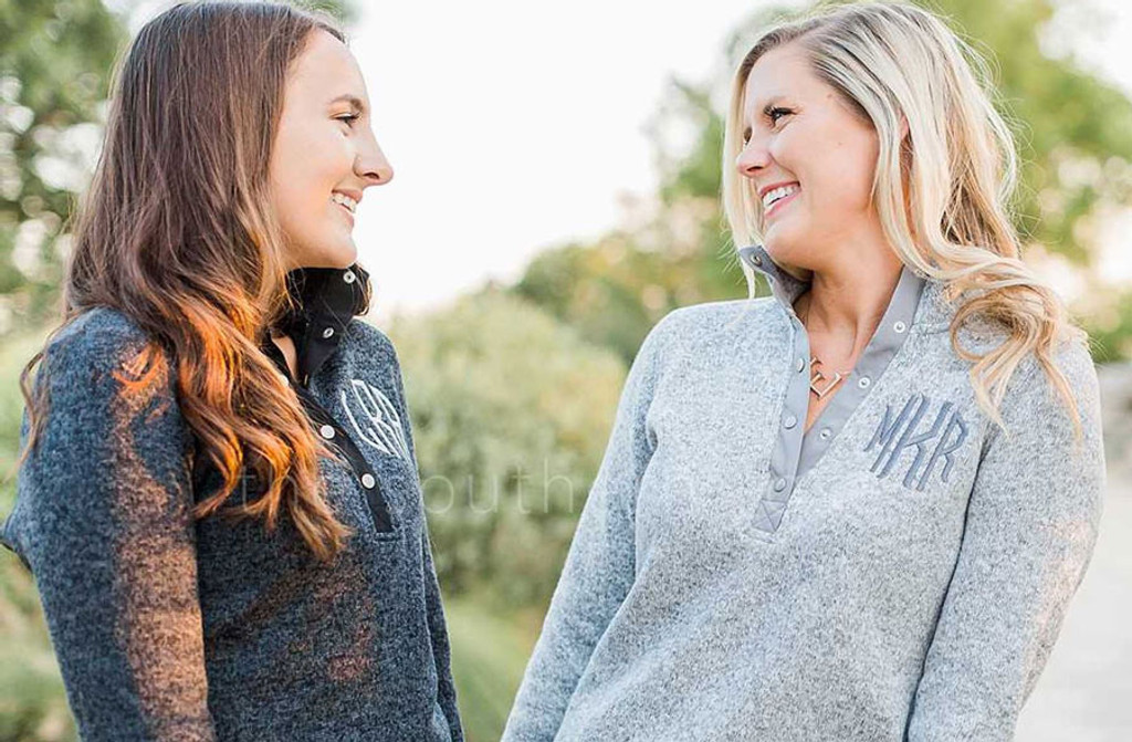 two women in monogrammed pullovers