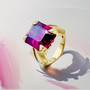 Unique women’s ring featuring large emerald-cut rhodolite garnet and ruby accents