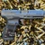 CANiK METE SF One Series compact 9mm pistol with optics-ready slide and black Cerakote finish, in store image on top of ammo casings and pointed to the right