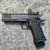 TYPE-A EG11 2011-style 9mm pistol with 5-inch match-grade barrel, Trijicon red dot optic, full-length Picatinny rail, aluminum grip module, and black finish, in store image