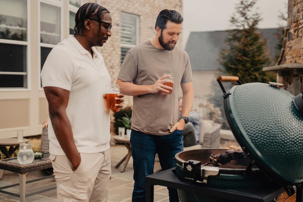 Family gathering around a Big Green Egg — backyard entertaining, golden hour lighting