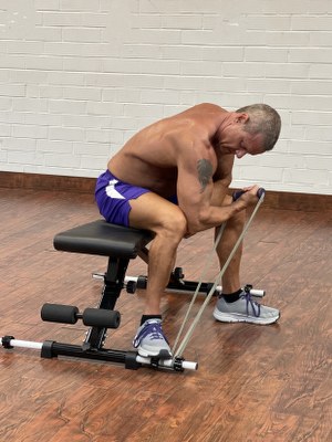Man Doing bicep exercise with intense resistance band holding intense resistance bands handle grips on intense band adjustable exercise bench