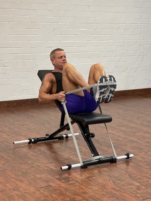 Man Doing legs exercise with intense resistance band holding intense resistance bands handle grips on intense band adjustable exercise bench