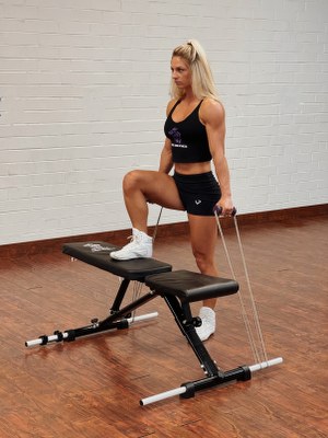 woman doing leg exercise with intense resistance band by standing on intense band adjustable exercise bench