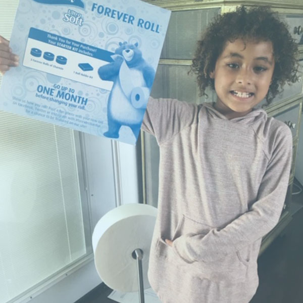 Child next to Charmin Forever Roll holding up the Forever Roll box insert