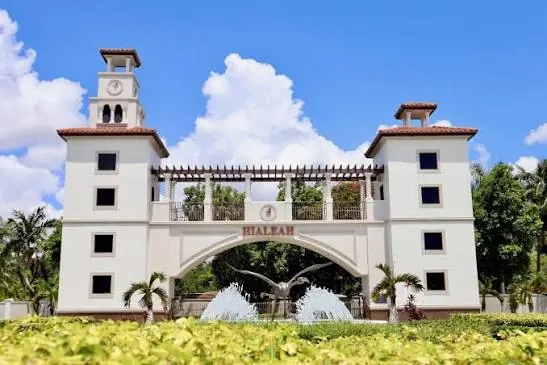 Un portal blanco de Hialeah con dos torres, una fuente y palmeras