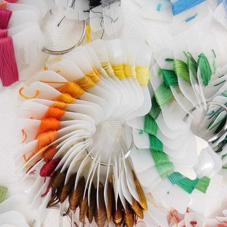 Embroidery floss wrapped on plastic bobbins held together on a DMC metal ring.