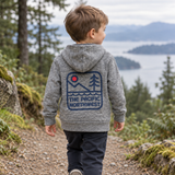 Child wearing the back of a grey zip hoodie with Pacific Northwest mountain, water and evergreen artwork