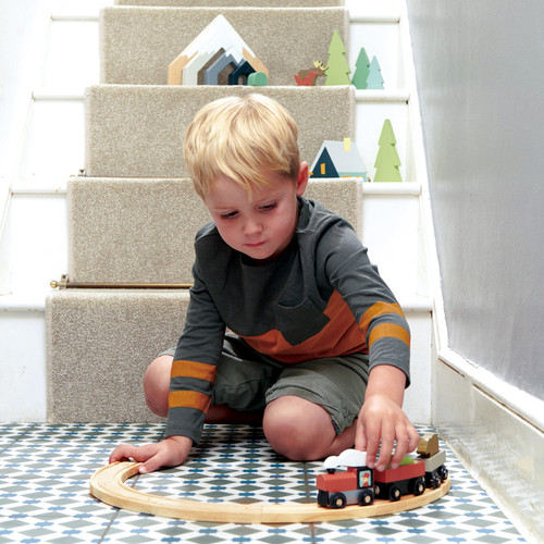 Boy playing with Tender Leaf Toys Treetops Train Set on floor