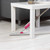 Spray mop with pink handle cleaning under white coffee table on light wooden floor