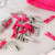 Pack of pink and grey plastic clothes pegs for laundry, shown on a surface.
