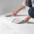 Hand brushing debris into a dustpan on light grey carpet