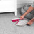 Grey dustpan and brush set with pink accents, shown upright against a cupboard.
