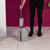 Grey flat mop head with removable pad, held by hand against pink background