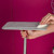 Grey flat mop head with removable pad, held by hand against pink background