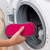 Hand using pink cleaning pad to remove brown stain from grey surface