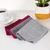 Hand using red cloth to clean coffee spill from white surface