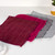 Set of three microfibre cloths in burgundy, pink and grey on a white surface