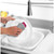 Pink and silver dish sponge cleaning a white plate in kitchen sink