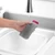 Grey textured washing-up sponge held under running tap in kitchen sink