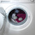 Washing machine with two grey laundry balls among pink and grey towels
