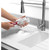 Bottle cleaning brush with pink handle washing a glass bottle at the sink