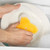 Person washing white plate with yellow sponge in soapy water