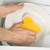 Hand washing a plate with a yellow sponge in a soapy kitchen sink