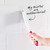White and pink cleaning brush with antibacterial bristles scrubbing white tiled wall.