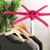Pink folding clothes airer with wooden hangers holding jumpers in grey and green.