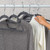 Grey and white jumpers on hangers, one selected by hand, for product listing.