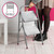 Two step silver folding step ladder with grooved treads, shown in use inside home