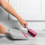 Pink silicone dish brush being rinsed under tap in kitchen sink