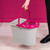 Grey mop bucket with bright pink wringer, shown being carried by handle.