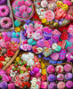 Close up of a vibrant Valentine’s Day dessert scene overflowing with sweets, including chocolates, cookies, donuts, and fruit.